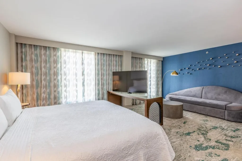 King room with a curved gray sofa and blue feature wall at Castle Hotel Orlando