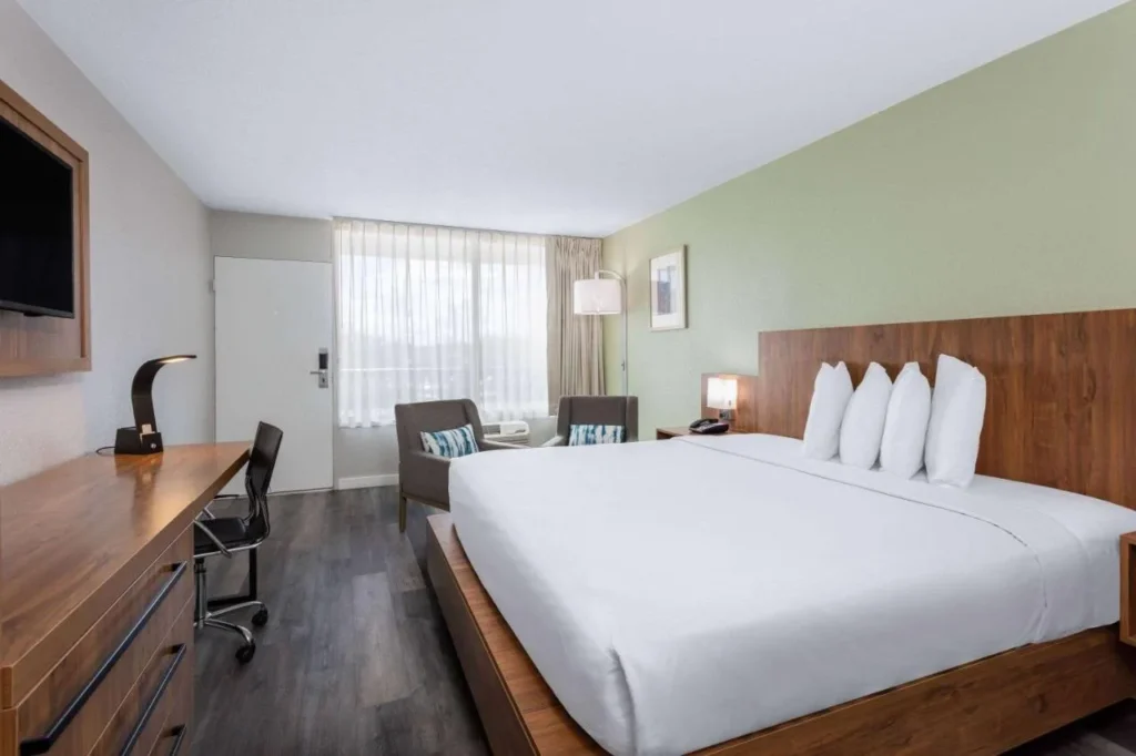 Habitaci&oacute;n King con escritorio, dos sillones y cabecero de madera en Ramada Altamonte Springs