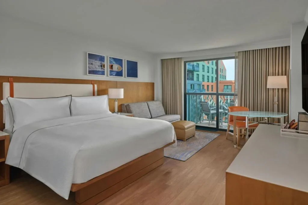 King room with a gray sofa, round table and balcony door, Walt Disney World Swan