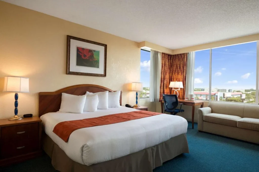 Habitaci&oacute;n con cama king con sof&aacute; y ventanas de esquina en Ramada by Wyndham Kissimmee Gateway