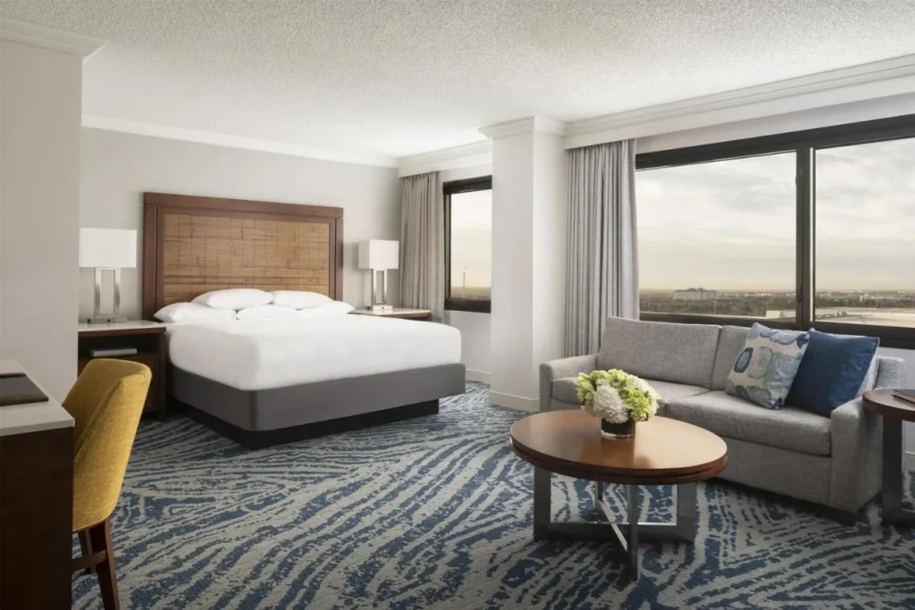 Habitaci&oacute;n con cama king con sof&aacute;, mesa de centro y amplios ventanales en Hyatt Regency Orlando