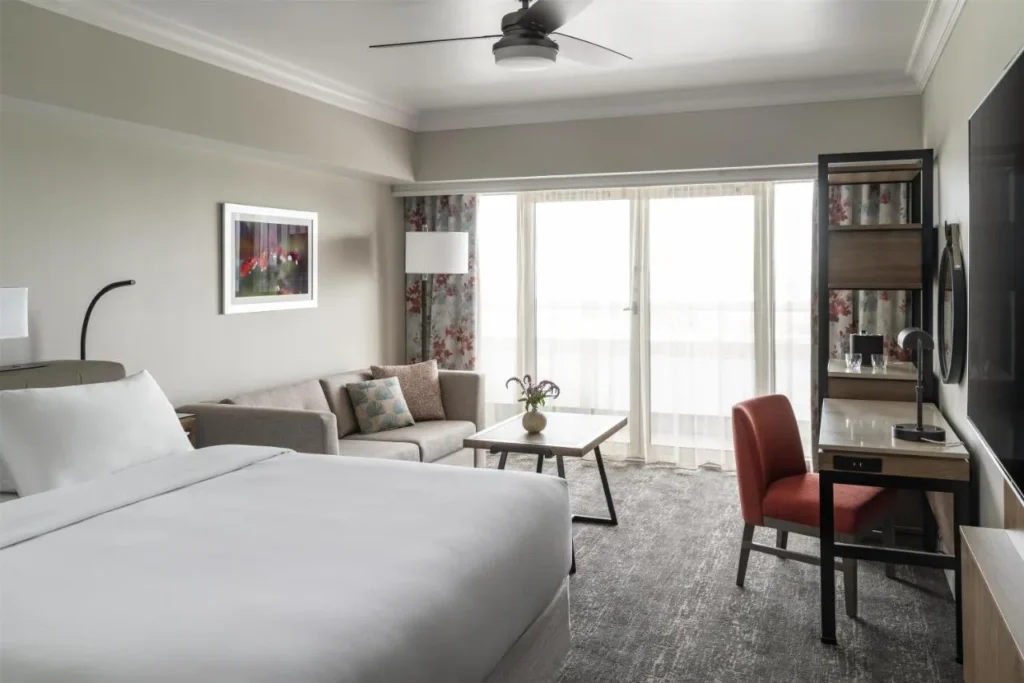 Habitaci&oacute;n con cama king con sof&aacute;, escritorio y puertas de balc&oacute;n en Hyatt Regency Orlando International Airport
