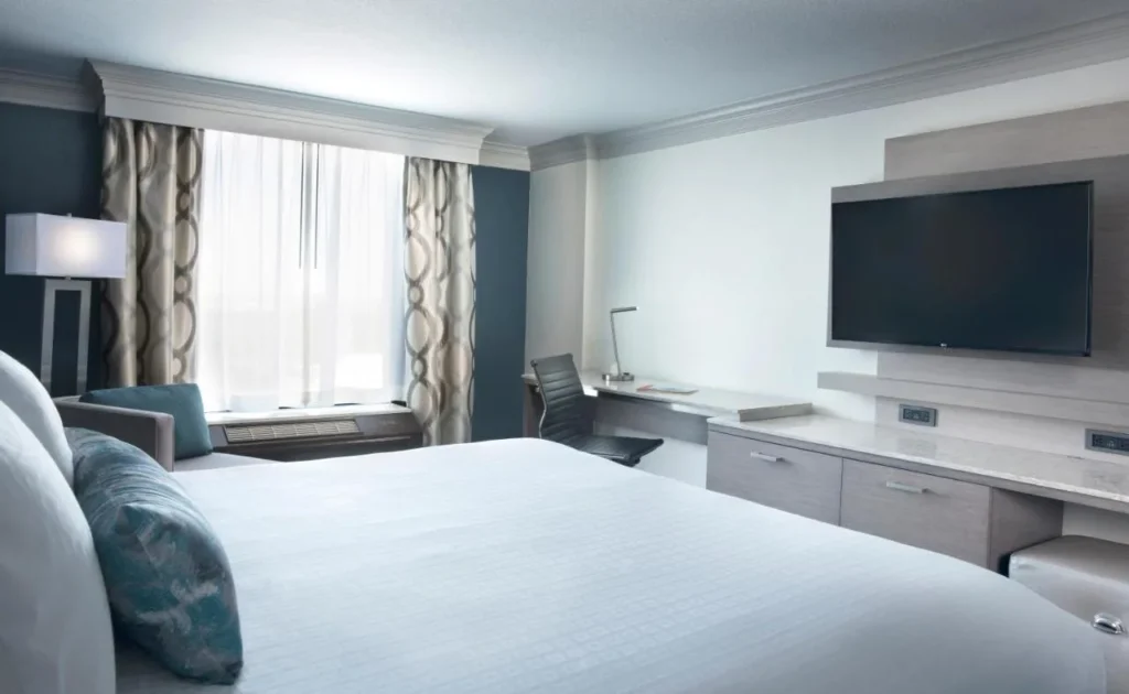 Habitación con cama king y TV de pared, escritorio largo y sillón en Rosen Centre Hotel