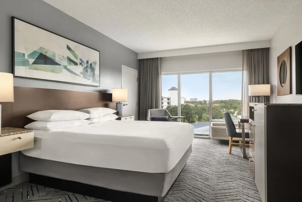 Habitaci&oacute;n King con una amplia ventana sobre las copas de los &aacute;rboles en Delta Hotels Orlando Celebration