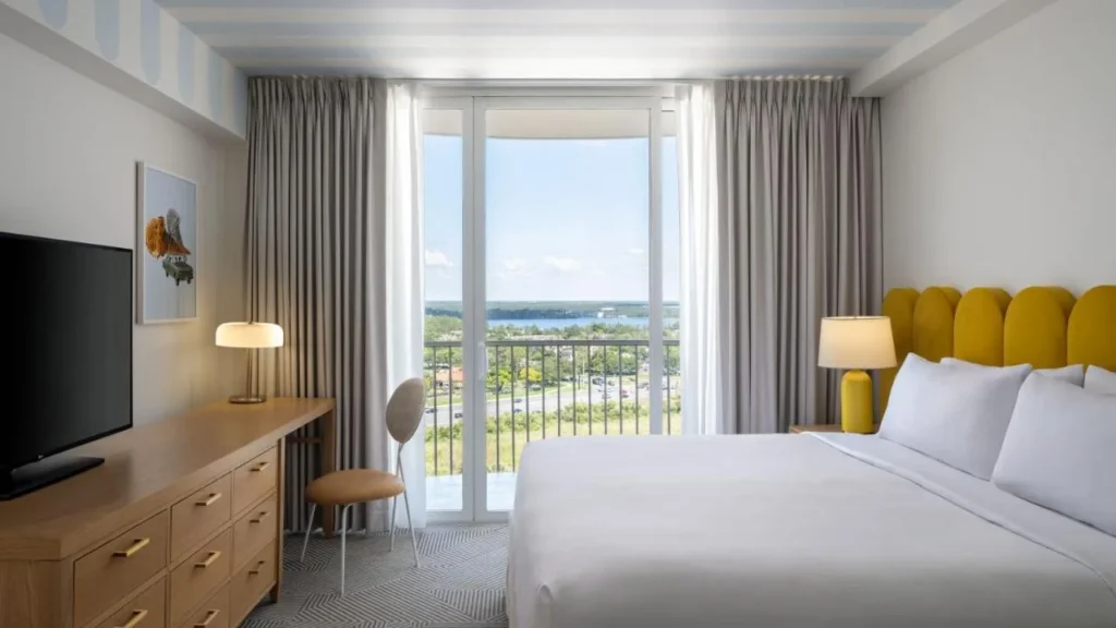 Habitaci&oacute;n con cama king con cabecero amarillo y puerta al balc&oacute;n con vista al lago en Renaissance Orlando Resort