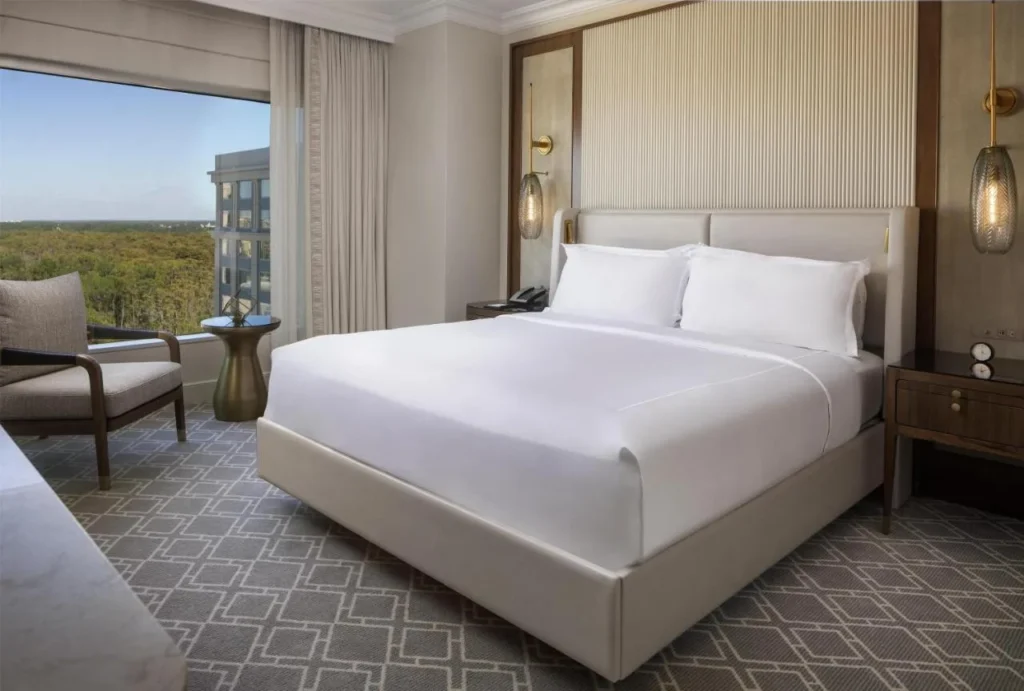 King room with an armchair and a wide window over the treetops at Waldorf Astoria Orlando