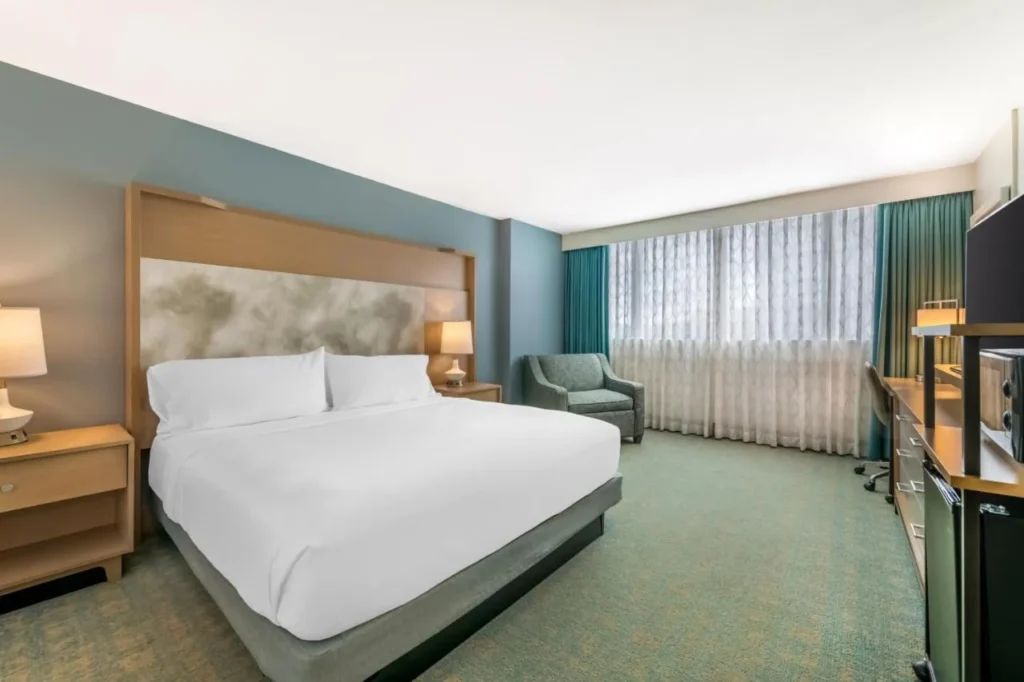 King room with an armchair and sheer-curtained windows at Holiday Inn Orlando Disney Springs