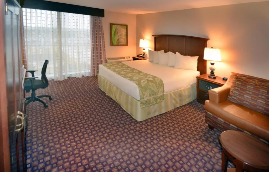 King room with armchair, desk and sliding glass door at Rosen Inn Closest to Universal