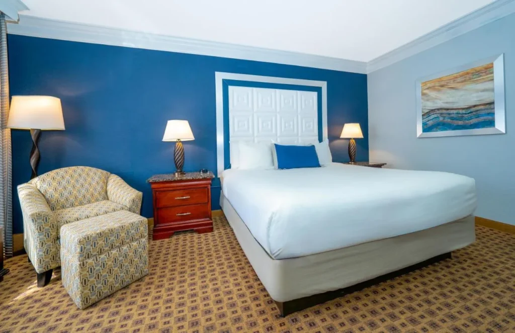King room with armchair, ottoman and blue accent wall at Rosen Plaza Hotel