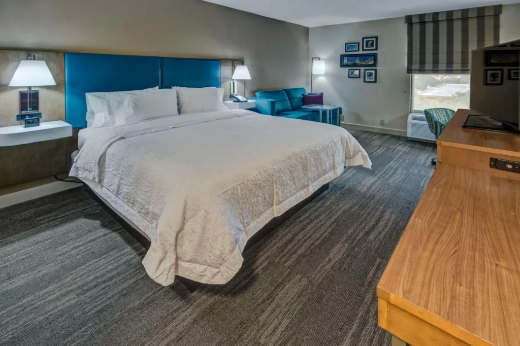 King room with blue headboard, teal sofa and flat-screen TV at Hampton Inn Orlando-Maingate South in Davenport