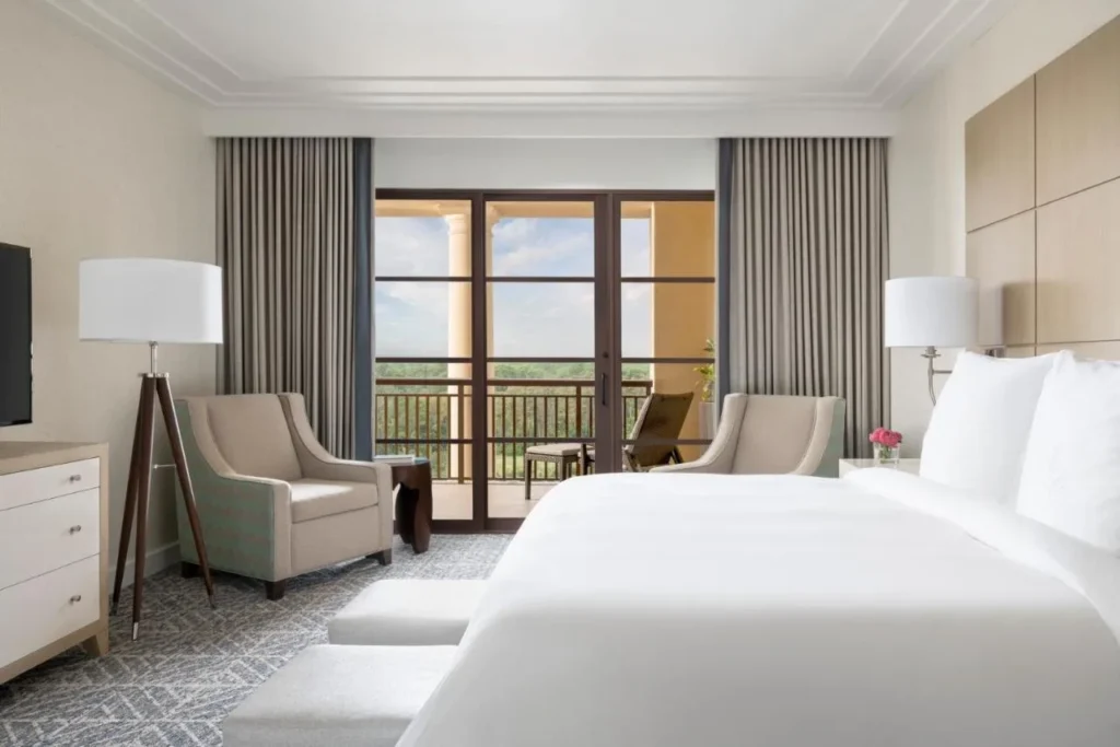 Habitación King con puertas de vidrio que dan a una terraza amueblada en Four Seasons Resort Orlando