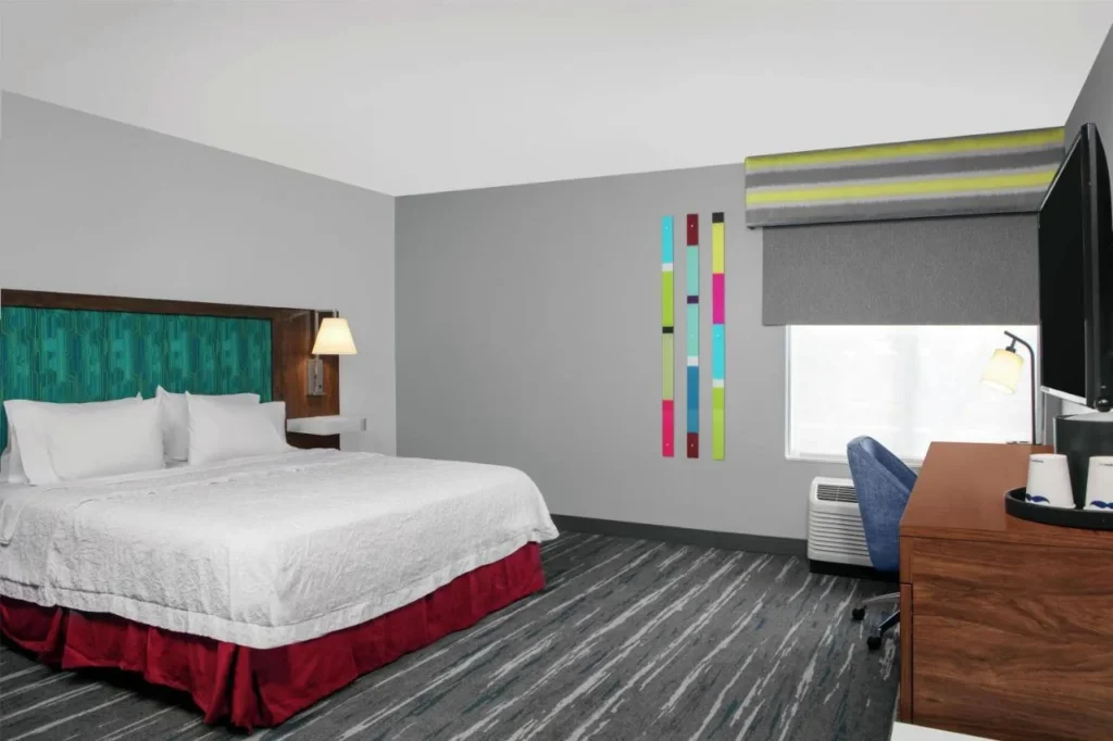 King room with red bed skirt, desk and window at Hampton Inn Orlando/Lake Buena Vista