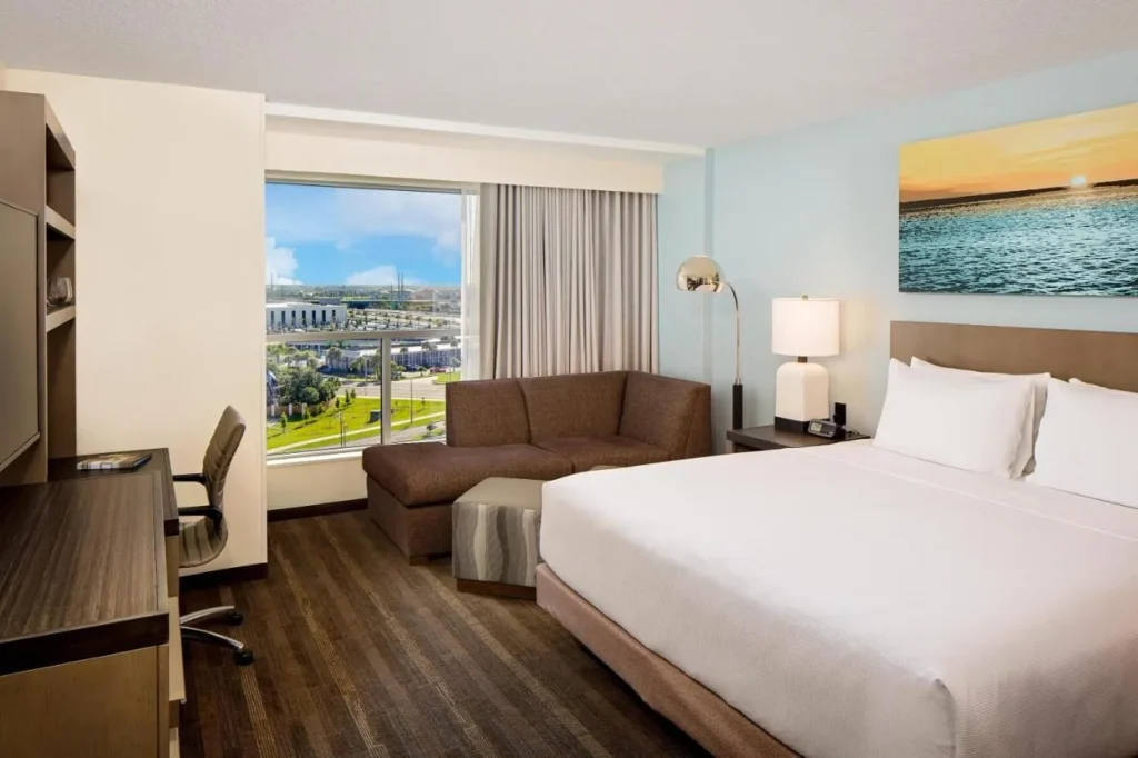 King room with sectional sofa, desk and window at Hyatt House across from Universal Orlando