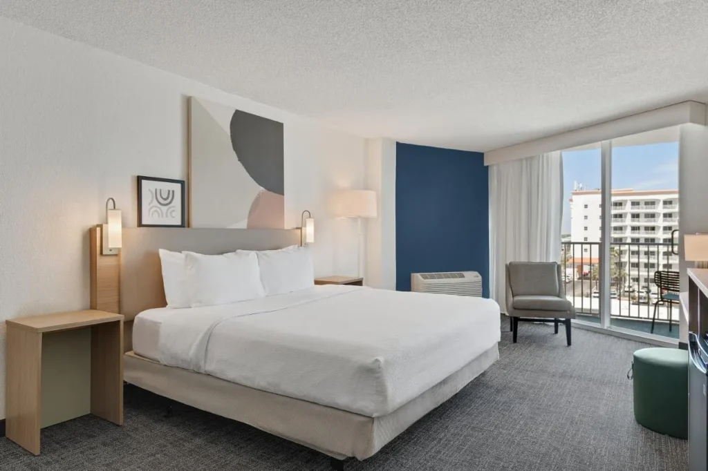Habitación con cama king y puerta corredera de cristal a un balcón en Spark by Hilton Ormond Beach Oceanfront