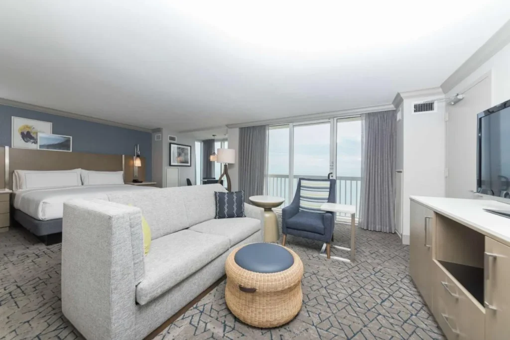 King room with sofa and floor-to-ceiling balcony doors facing the ocean at Hilton Melbourne Beach Oceanfront