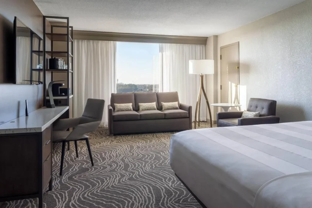 Habitaci&oacute;n con cama king, sof&aacute;, escritorio y ventana en Marriott Orlando Airport Lakeside