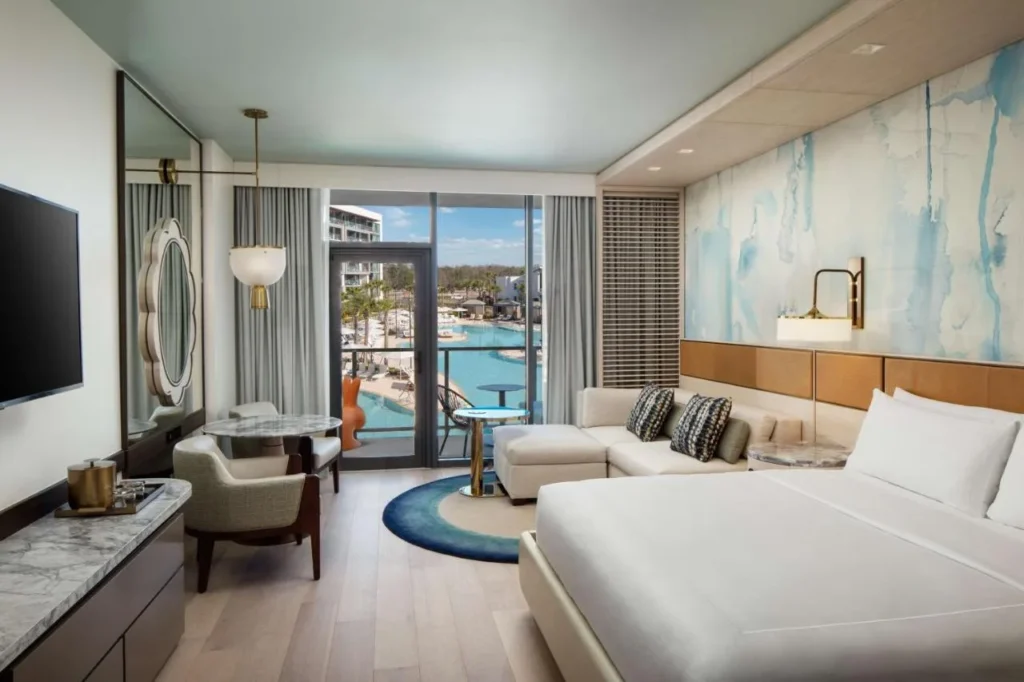 Habitación con cama king con sofá y balcón con vistas a la piscina en Conrad Orlando