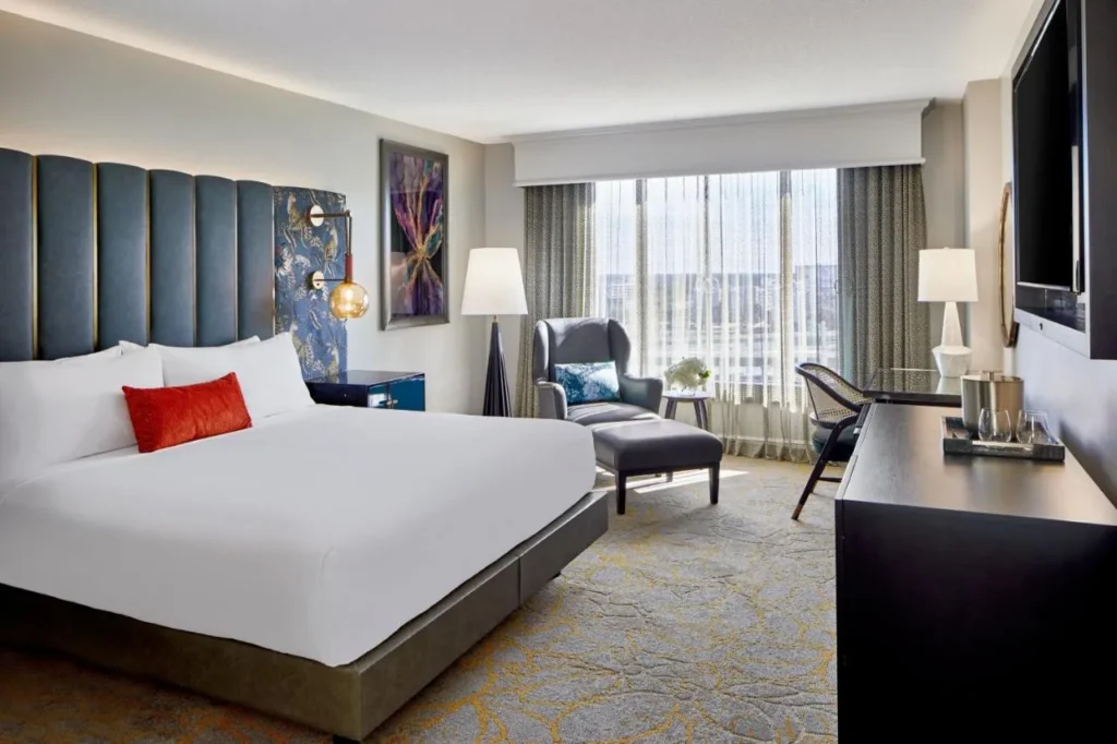 Habitaci&oacute;n King con cabecera alta tapizada de color azul, sill&oacute;n y ventana con vista a la ciudad en el Hotel Beauden Orlando