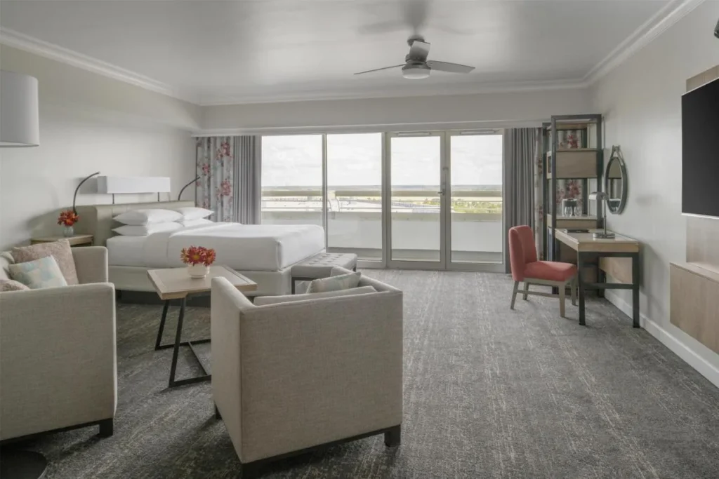 Habitaci&oacute;n King con dos sillones y puertas de vidrio de piso a techo en el Hyatt Regency Orlando International Airport