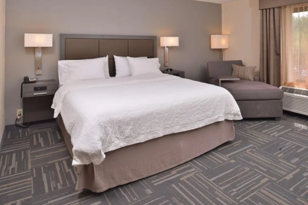 King room with white bedding, chaise lounge and window at Hampton Inn Closest to Universal
