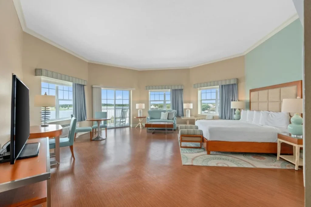 Habitaci&oacute;n king con suelo de madera, sof&aacute; y puerta de balc&oacute;n frente al lago en The Waterfront Inn