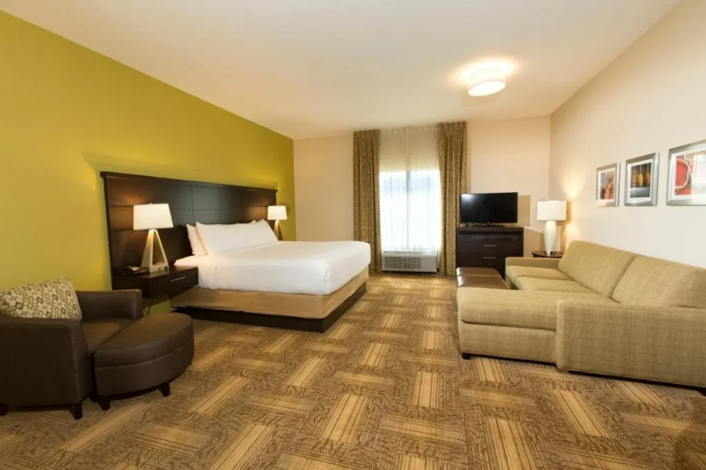 Suite estudio con cama king y sofá seccional, sillón y TV en Staybridge Suites Orlando at SeaWorld