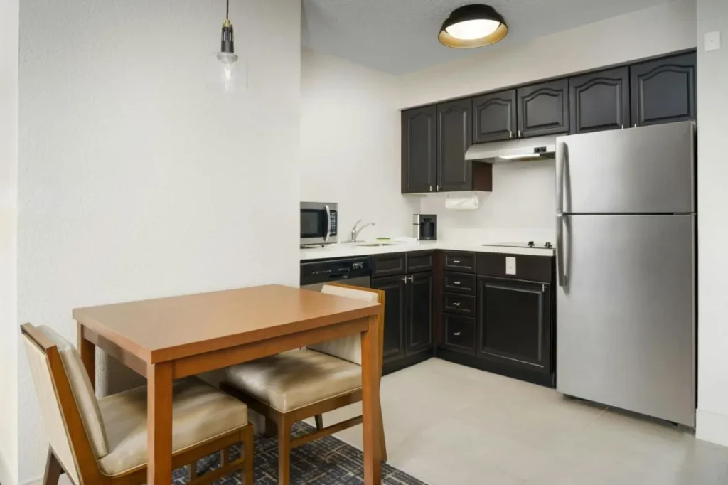 Cocina con nevera de tama&ntilde;o completo, placa de cocina, lavavajillas y mesa de comedor en Residence Inn Lake Buena Vista