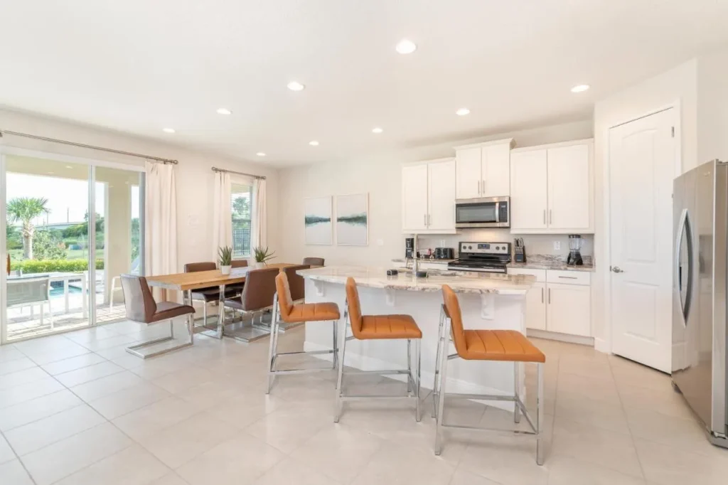 Kitchen with white cabinets, island seating and a dining table in an Encore Resort home