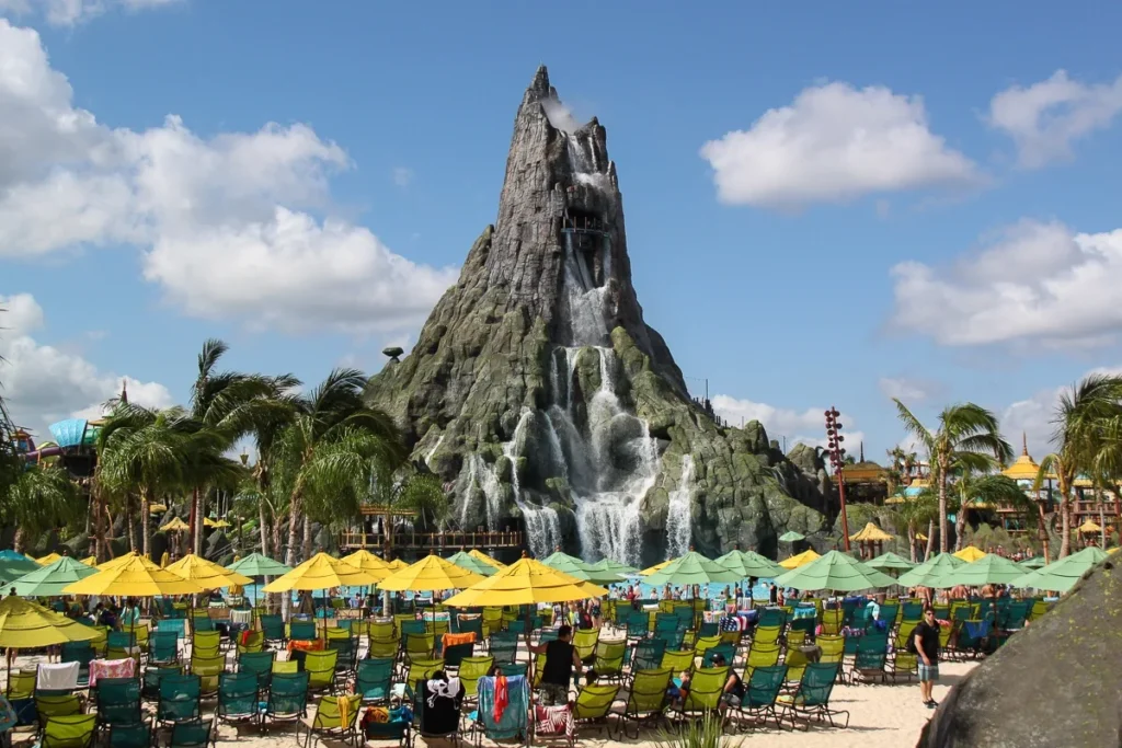 Krakatau volcano with waterfalls above rows of loungers and yellow and green umbrellas at Universal Volcano Bay