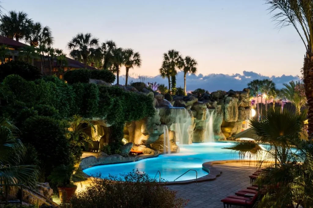 Piscina de la laguna y cascadas de roca iluminada al atardecer en Hyatt Regency Grand Cypress