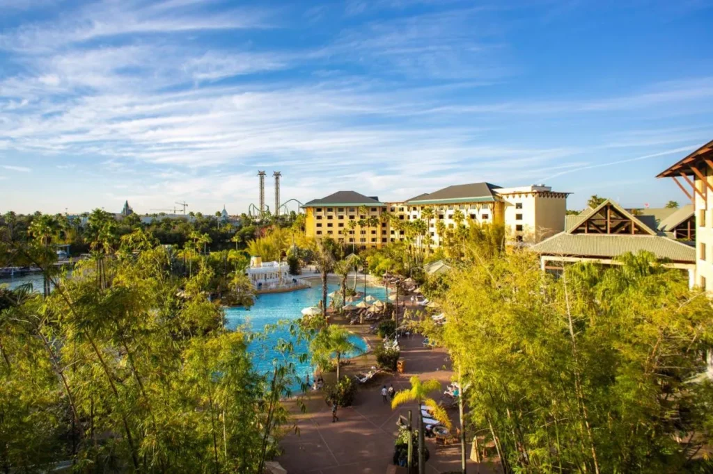 Lagoon-style pool with palms and umbrellas below the yellow towers of Loews Royal Pacific Resort