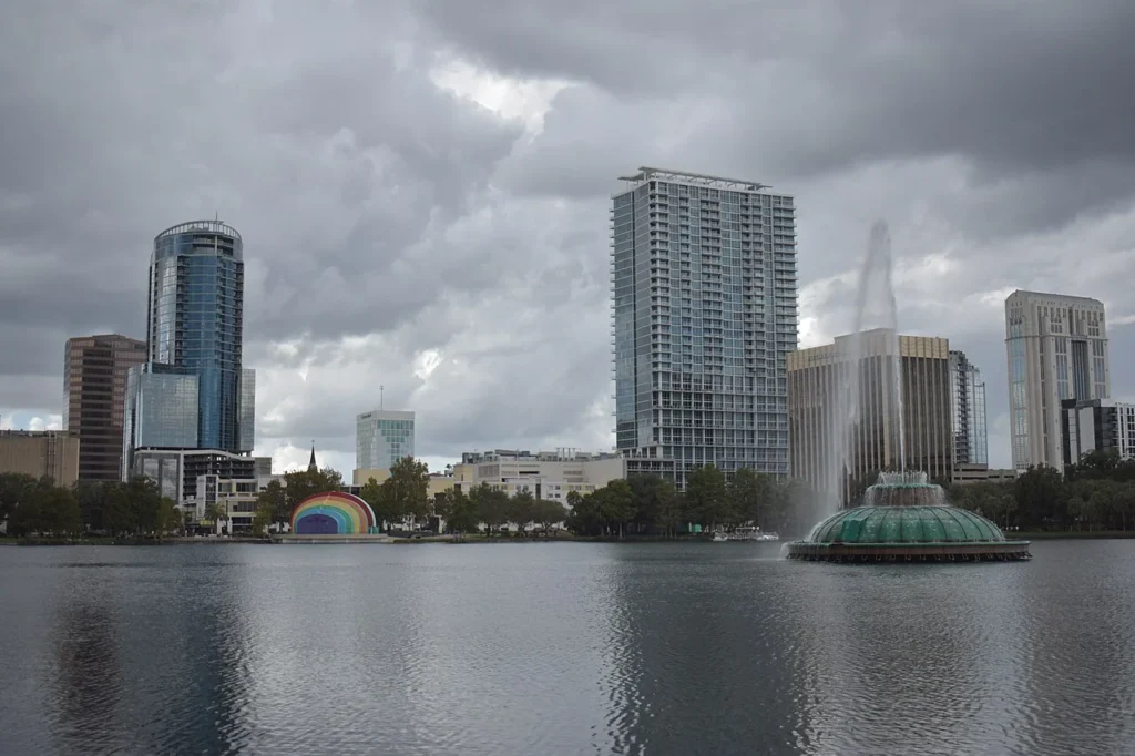 Lake Eola fountain, the rainbow Walt Disney Amphitheater and downtown Orlando skyline under clouds