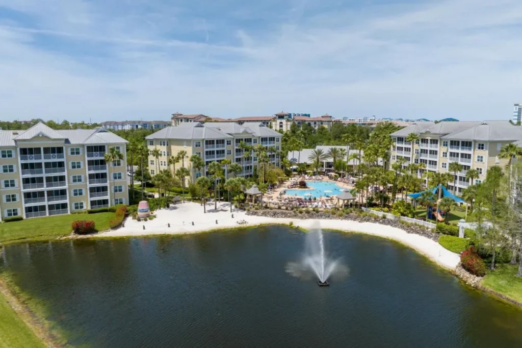 Fuente del lago, playa de arena y piscina entre los edificios de estilo Cayo Hueso en Sheraton Vistana Villages