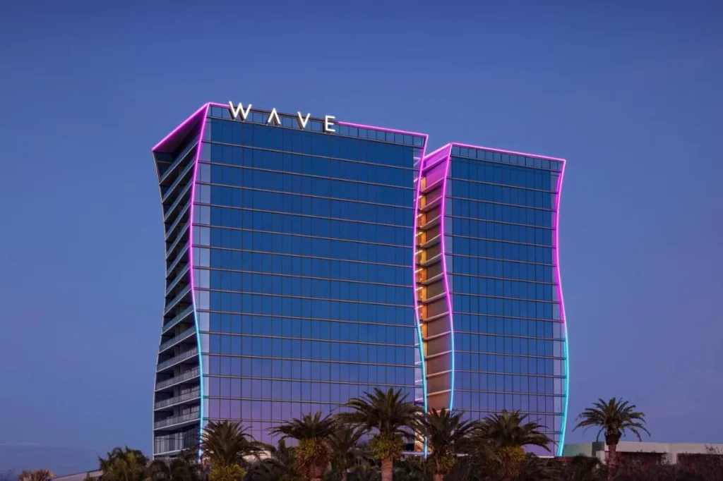 Las torres de vidrio curvadas del Lake Nona Wave Hotel se iluminaron de rosa y azul al atardecer sobre las palmeras