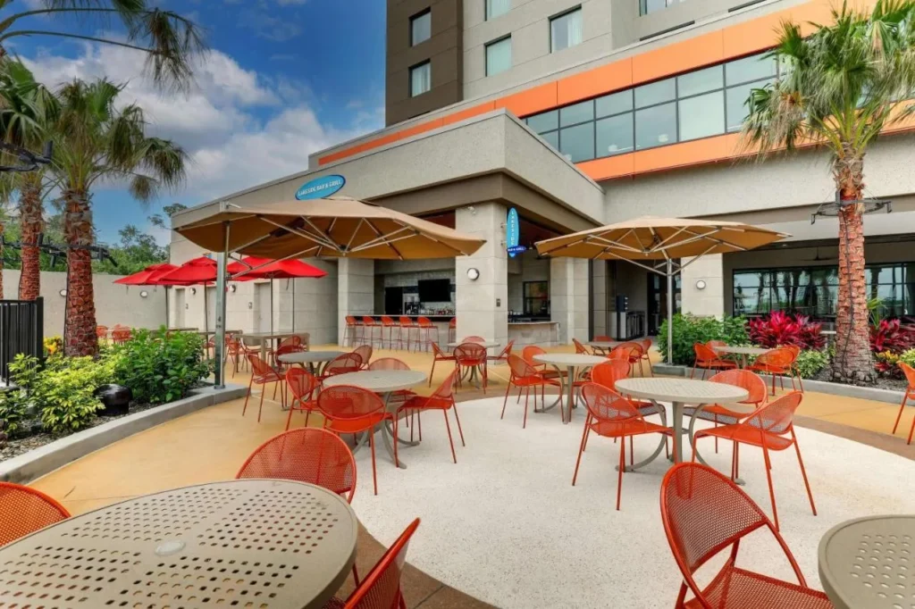 Lakeside Bar & Grill patio with orange chairs and umbrellas at Drury Plaza Hotel Orlando