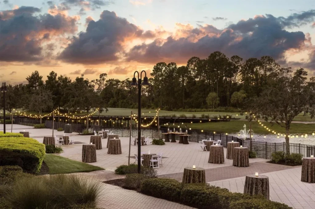 Lakeside event terrace with string lights and high-top tables at dusk, Waldorf Astoria Orlando