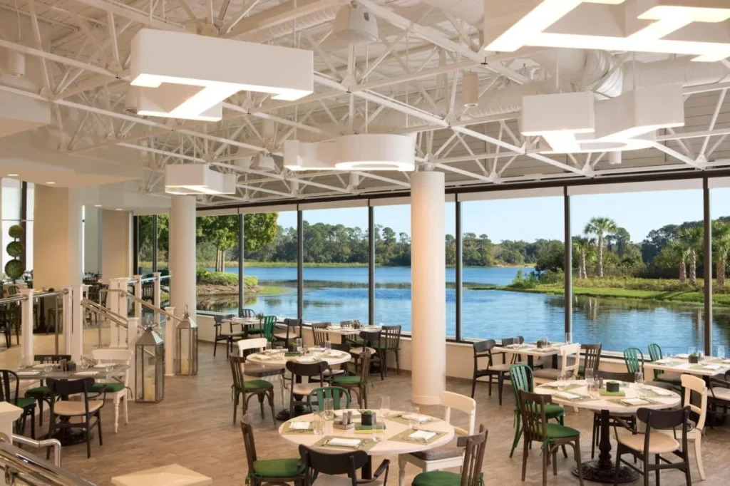 Lakeview restaurant with tall windows and green chairs at Hilton Orlando Buena Vista Palace