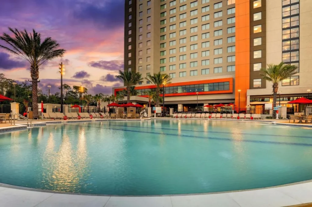 Large outdoor pool and hotel tower at dusk at Drury Plaza Hotel Orlando Disney Springs Area