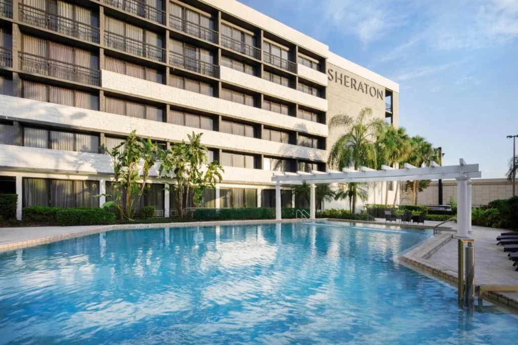 Gran piscina al aire libre con p&eacute;rgola y palmeras frente al Sheraton Orlando North en Maitland