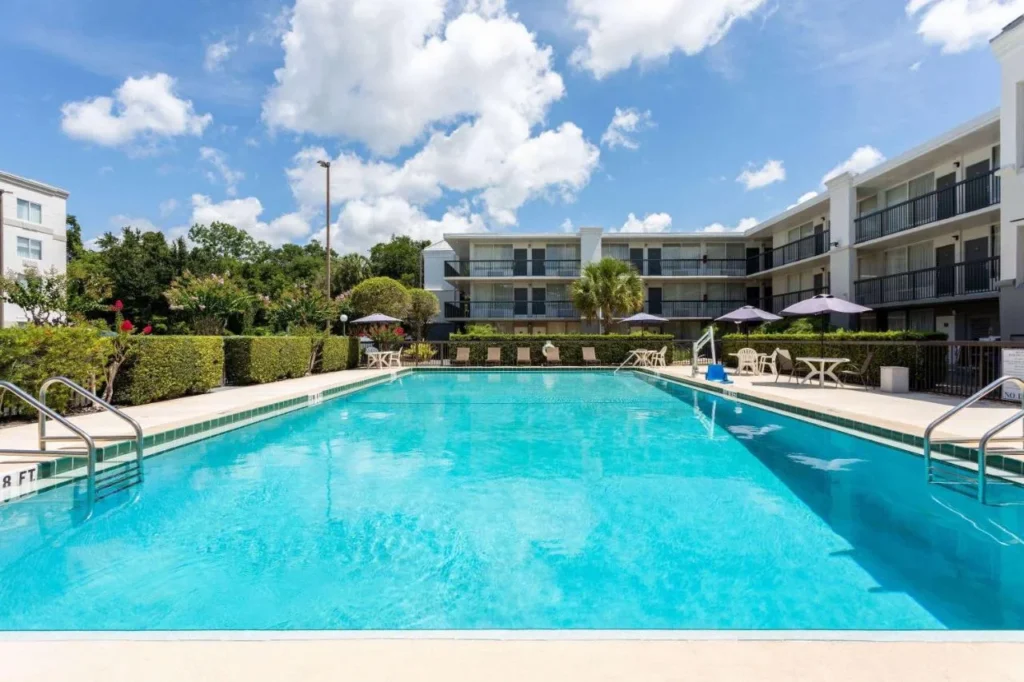 Gran piscina al aire libre con sombrillas y alas de habitaci&oacute;n de tres pisos en Ramada Altamonte Springs