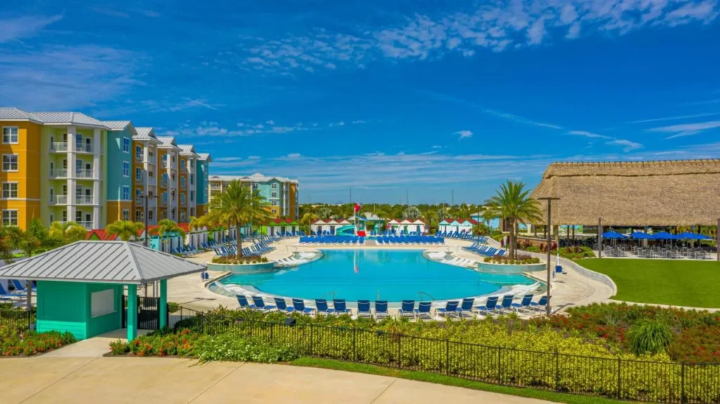 Gran piscina, bar con techo de paja y coloridos edificios de suites en Embassy Suites Orlando Sunset Walk