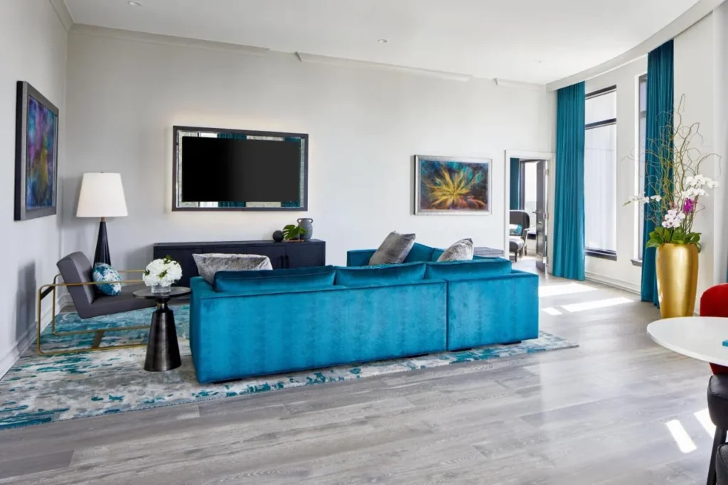 Large suite living room with teal sectional sofa and light wood floors at Hotel Beauden