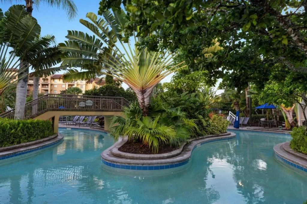 Lazy river serpenteando bajo una pasarela entre plantas tropicales en Club Wyndham Bonnet Creek
