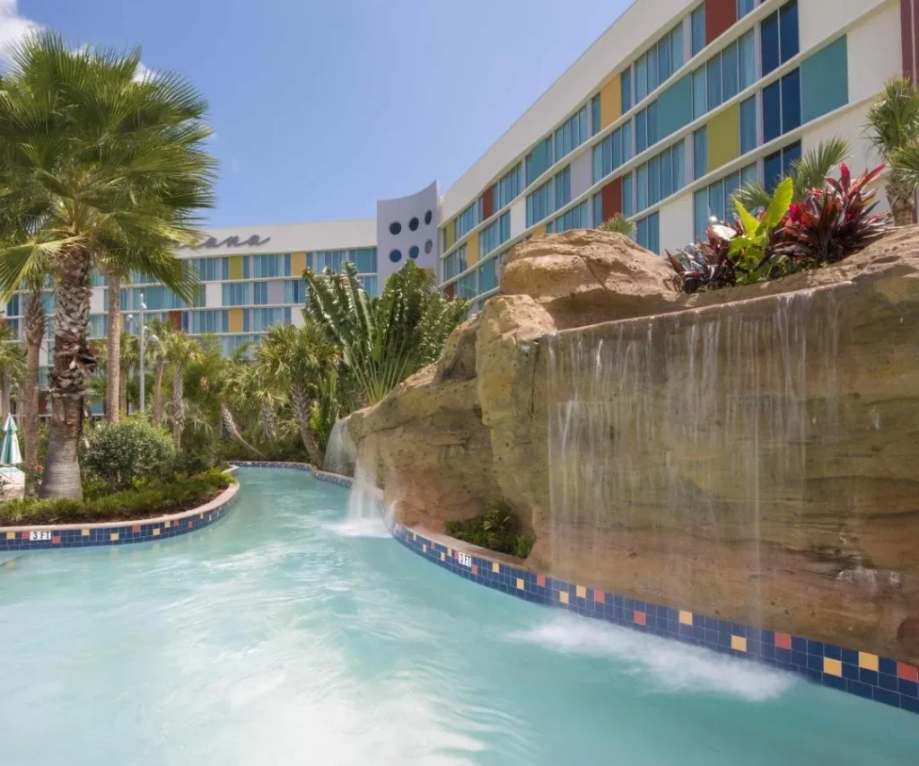 R&iacute;o perezoso con cascada de roca junto a un edificio de invitados en Cabana Bay Beach Resort