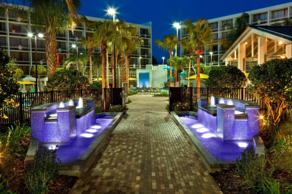 Fuentes iluminadas bordean la pasarela hacia la piscina y el tobog&aacute;n acu&aacute;tico en Sheraton Lake Buena Vista