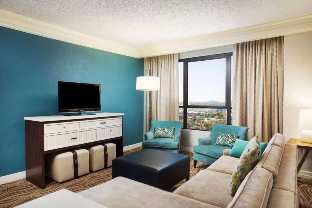 Living room with a teal accent wall, sectional sofa and city-view window, Wyndham Lake Buena Vista