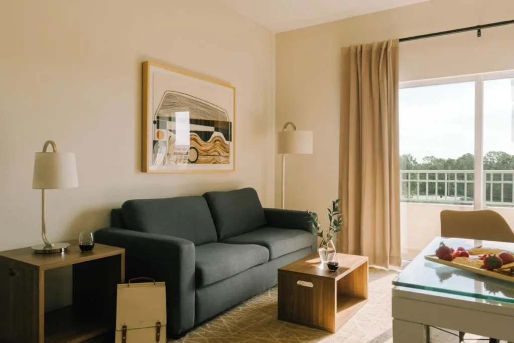 Sala de estar con sof&aacute; gris, mesa de centro y puerta del balc&oacute;n en The Point Hotel & Suites