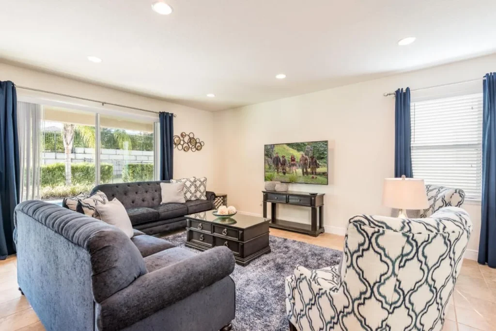 Living room with gray sofas, two patterned armchairs and a TV in an Encore Resort home