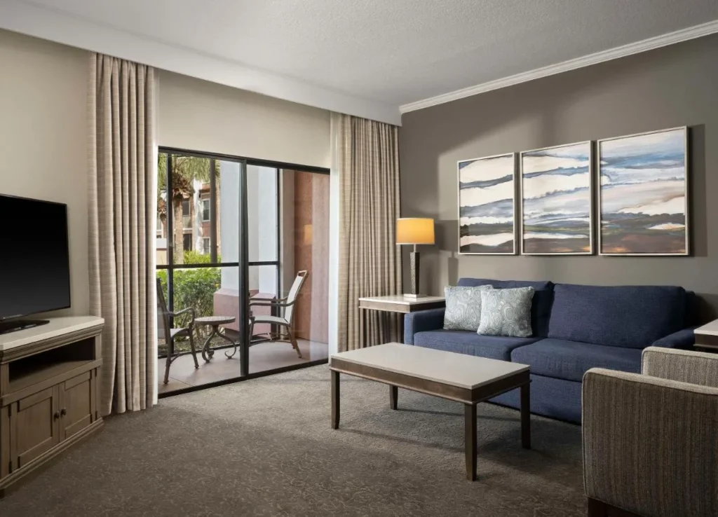 Sala de estar con sof&aacute; azul marino, mesa de centro y puerta del patio en Caribe Royale Orlando
