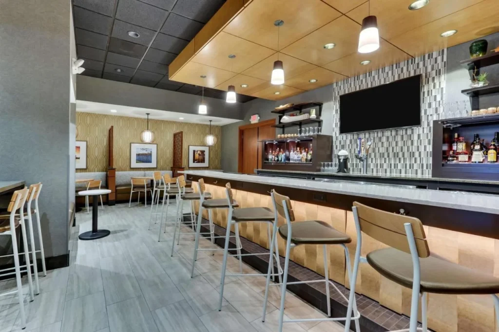 Lobby bar counter with stools, TV and liquor shelves at Drury Inn & Suites near Universal